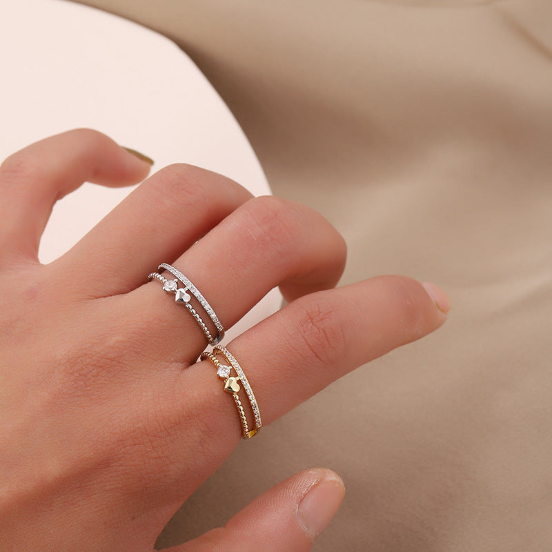 A woman wearing a silver and a gold heart-shape-ring on the same hand