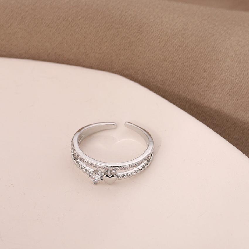 A heart shaped silver ring over a table