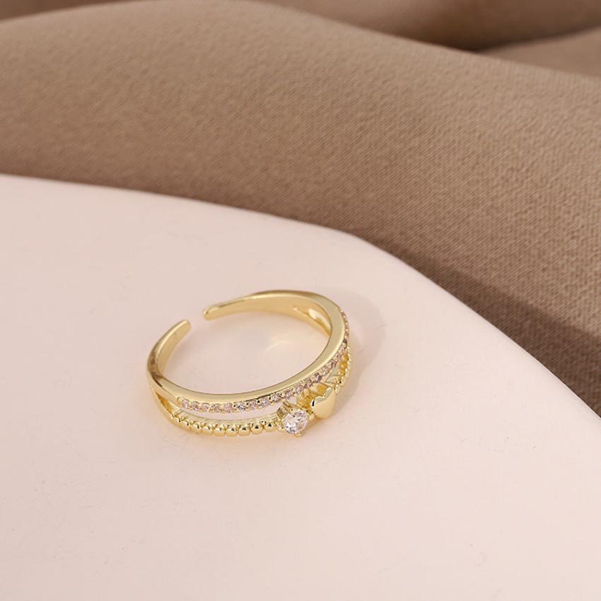 A gold ring with a heart shape and diamonds on a table