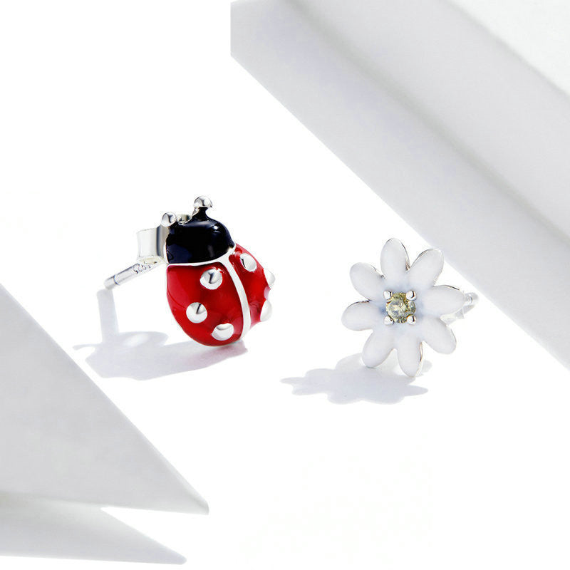Close view of a pair of silver ladybug theme earrings in a white canvas