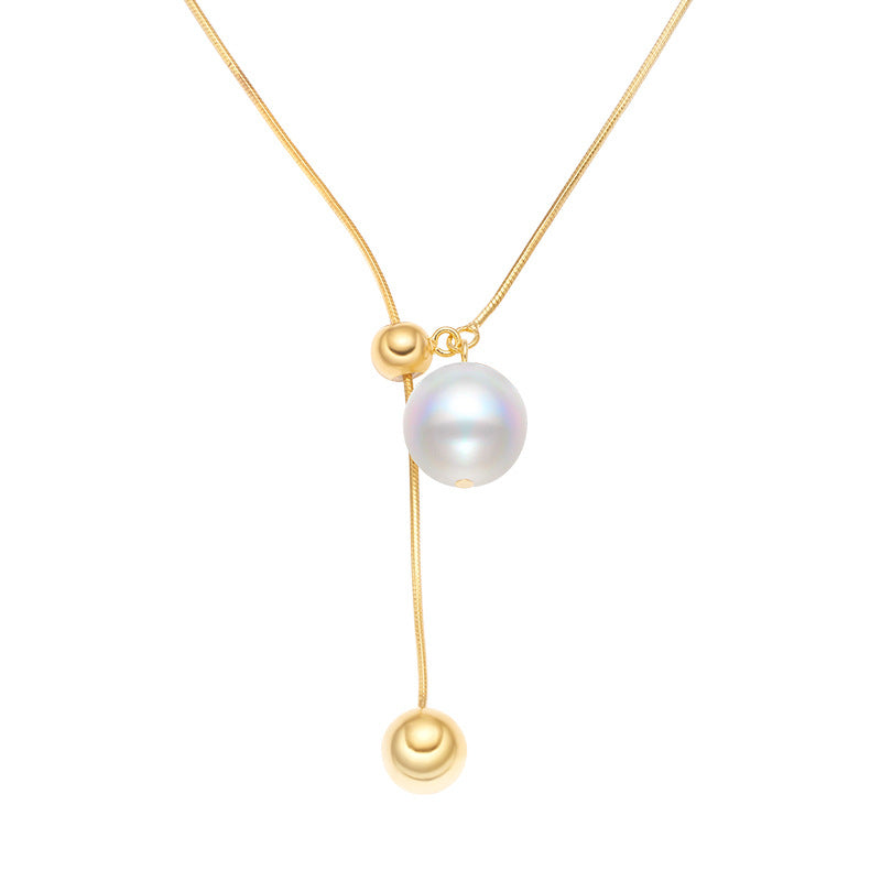 A gold woman's necklace with a white pearl in a white background