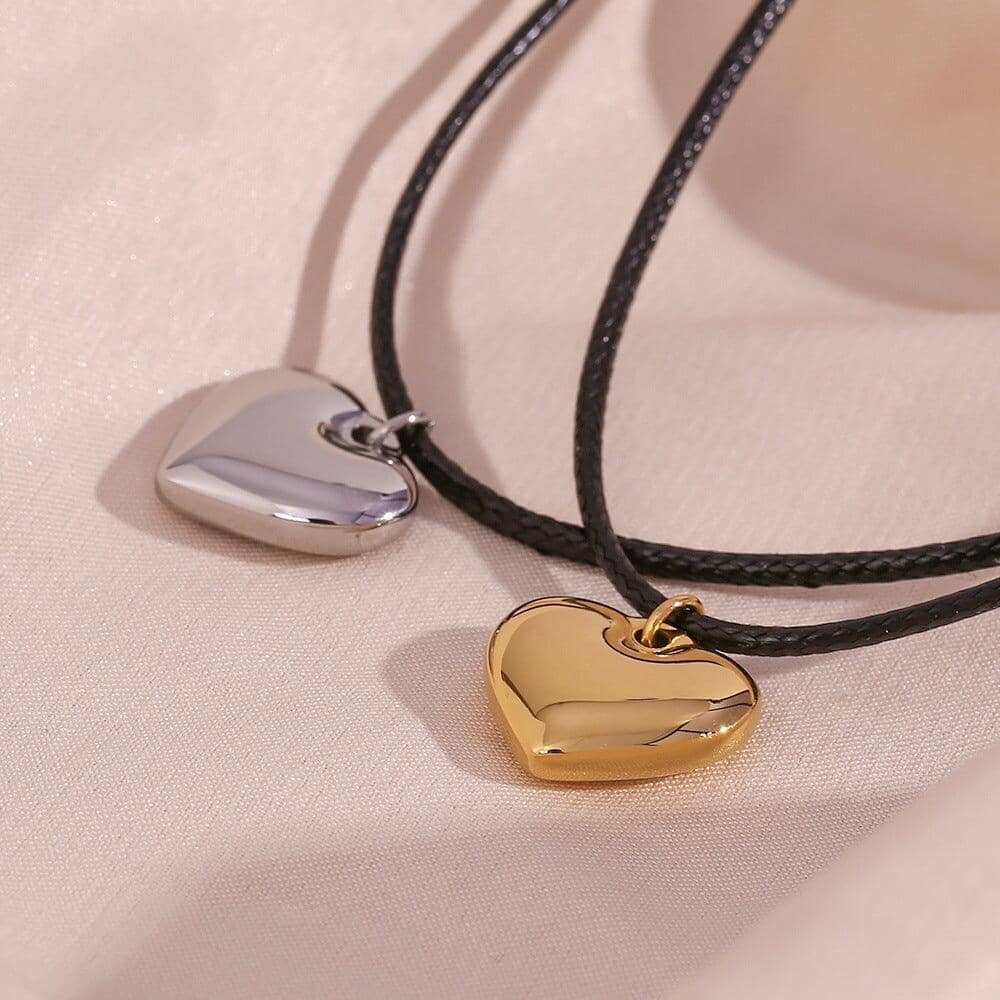 gold and silver rope necklaces with heart pendants on a fabric texture background