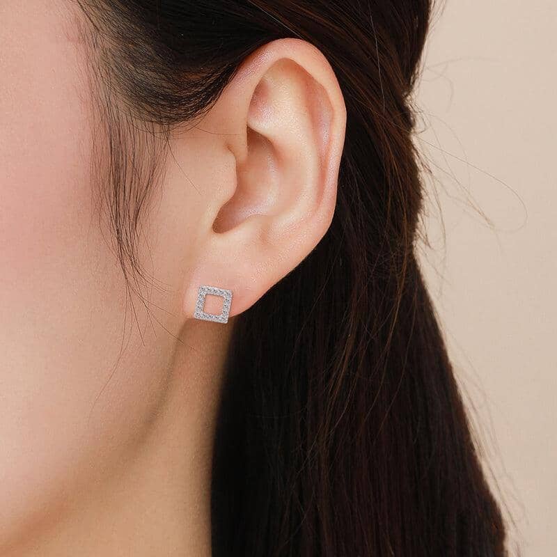 a woman wearing silver square earrings