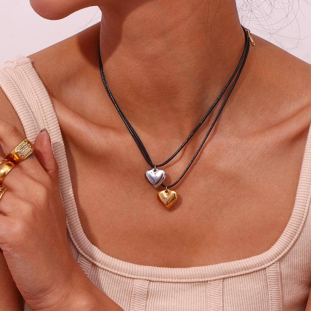 A woman wearing two rope chains with a silver and a gold heart pendant