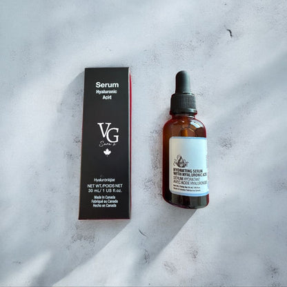 A container of serum hyaluronic acid besides its black packing with a logo a both over a marble countertopd