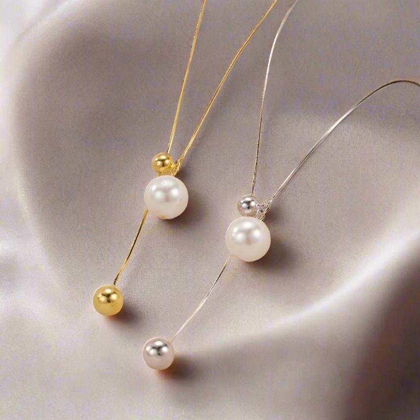 A silver and a gold pearl necklace on an elegant fabric
