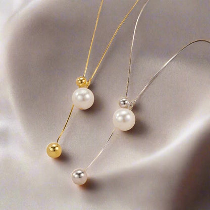 A silver and a gold pearl necklace on an elegant fabric